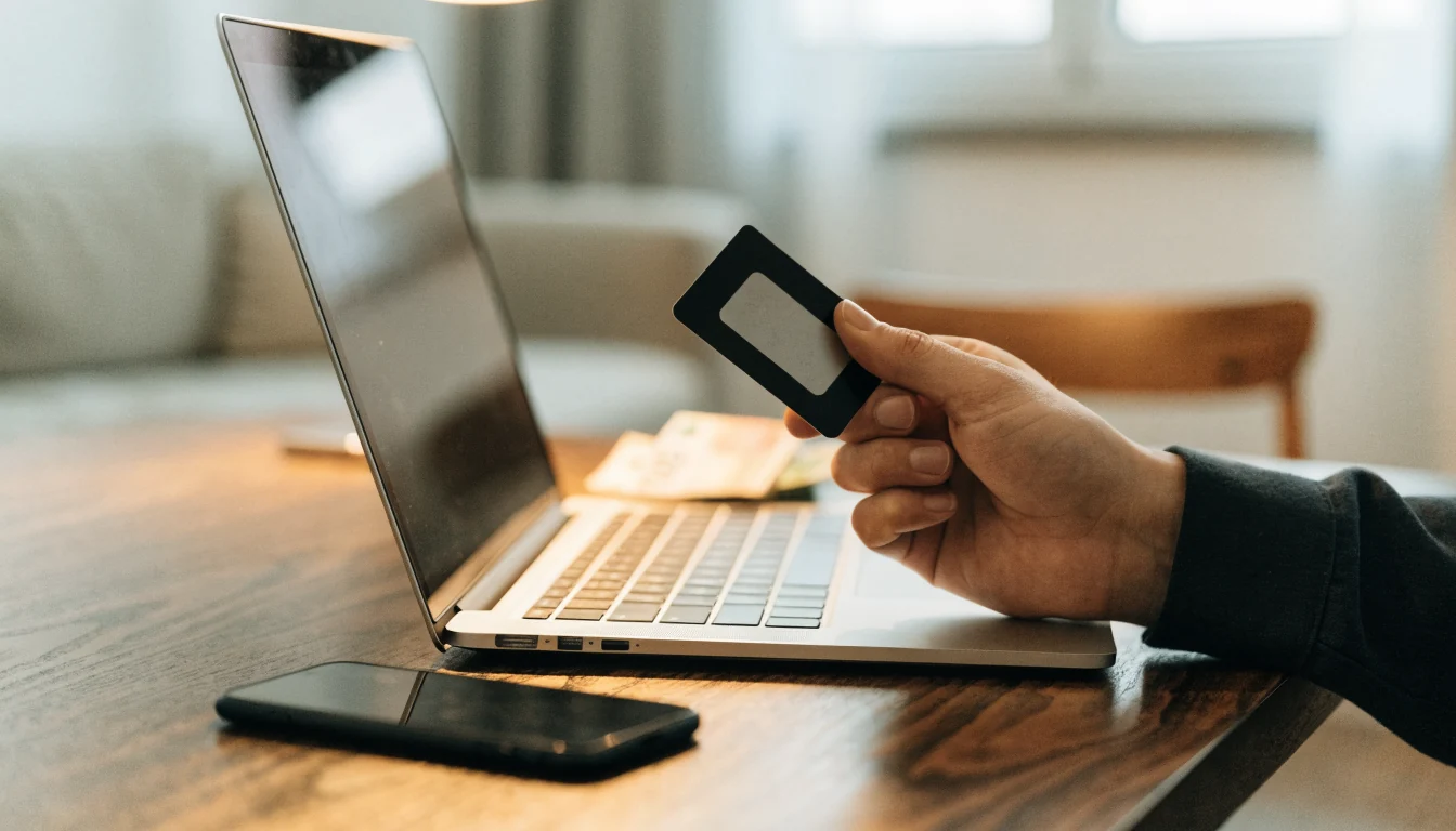 Hand hält eine Flexepin-Prepaid-Karte neben Laptop auf Schreibtisch